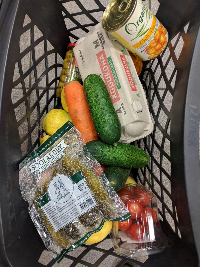 Shopping cart basket full of pickles, carrots, kirby cucumbers, chickpeas in a can, tomatoes and eggs at Rimi in Tallinn, Estonia.
