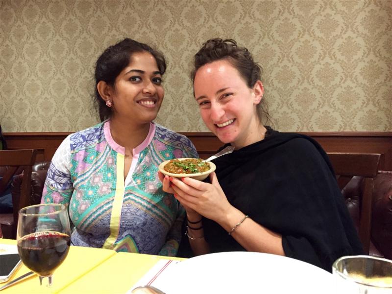 Women smiling with vegetarian Indian food at a restaurant in downtown Mumbai, India.