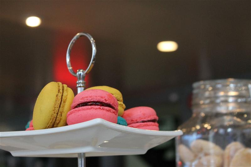 Yellow and pink macarons on a white tray in a cafe.