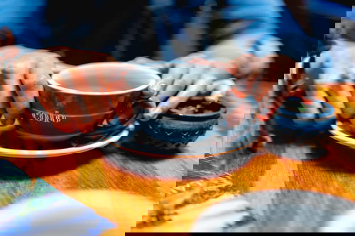 Woman with hands on a big blue coffee cup on a wooden table in Bogota
