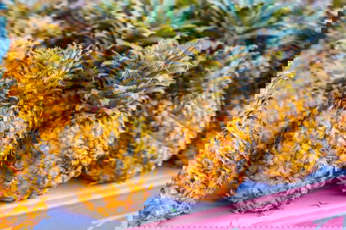 Pineapples for sale on a white and pink wooden ledge