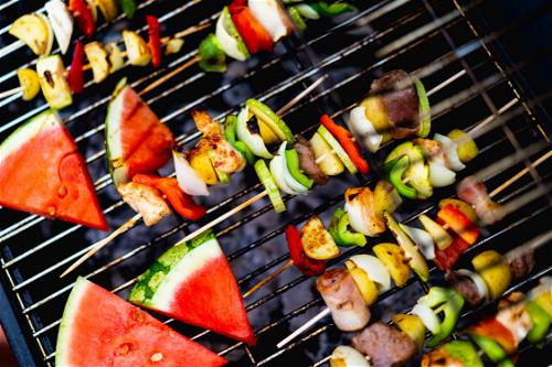 Grilling watermelon and vegetable kebabs on grill