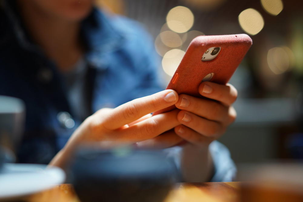 A woman is using a cell phone while sitting at a table.