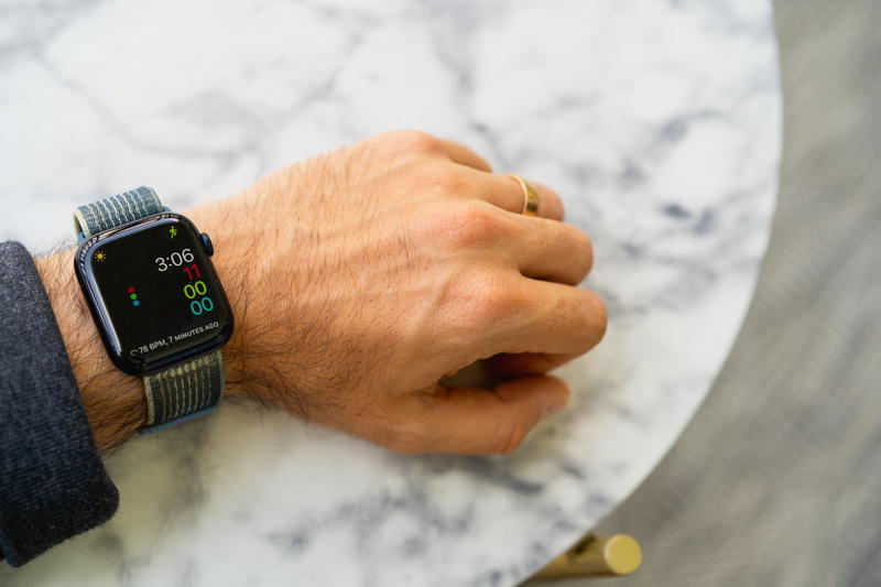 A person wearing an apple watch on a marble table.