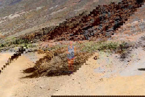 Woman hiking on a wide desert hiking trail with red desert rocks in El Teide National Park in Spain