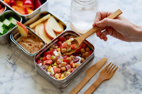 A person is holding a metal container with food in it.