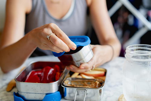 A woman is putting food into a container.