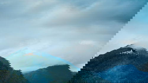 A church on top of a mountain under a cloudy sky.