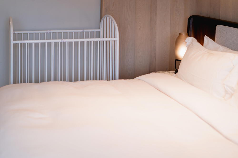 A white crib in the corner next to the bed at the Muir Hotel in Halifax.