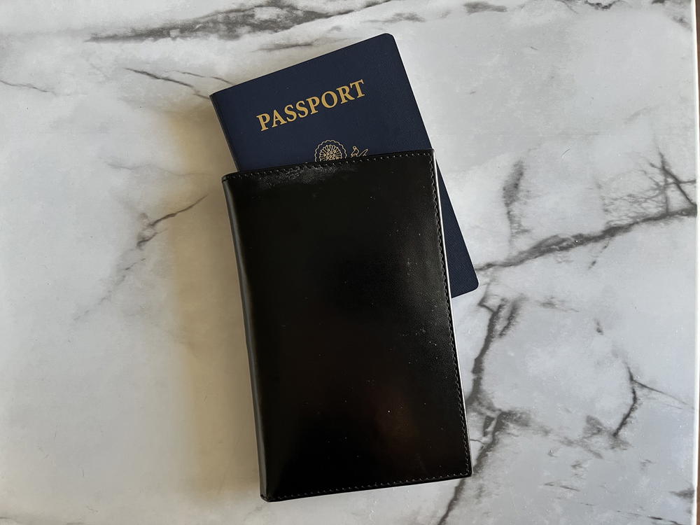 A black passport holder on a marble table.