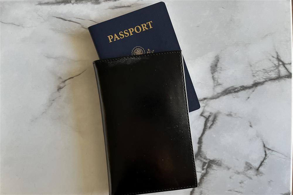 A black passport holder on a marble table.