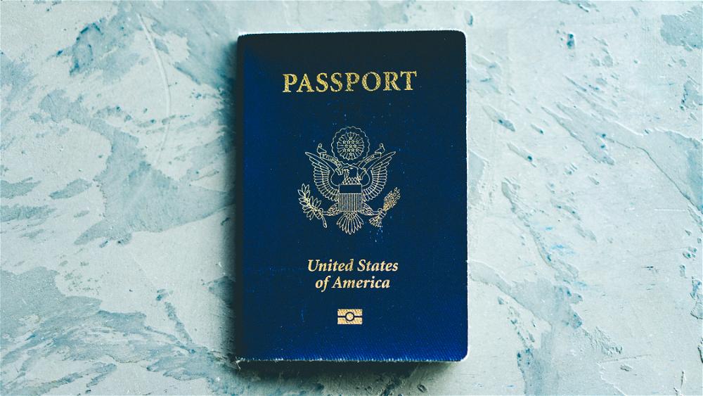 A blue passport sitting on a blue surface.