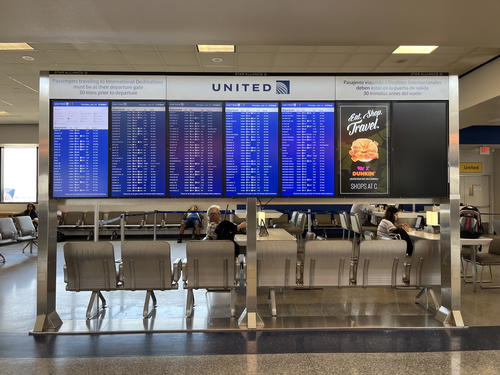 A large screen showing flight information at an airport.