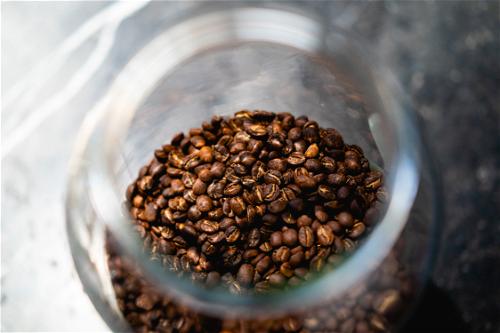 Coffee beans in a glass jar on a table.