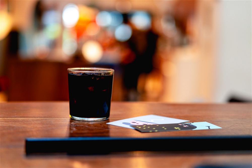A glass of black liquid on a wooden table.
