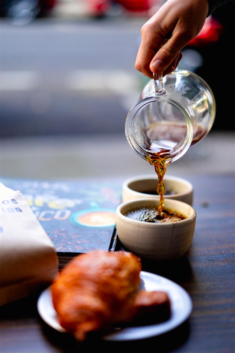 A person pouring a cup of coffee onto a plate.