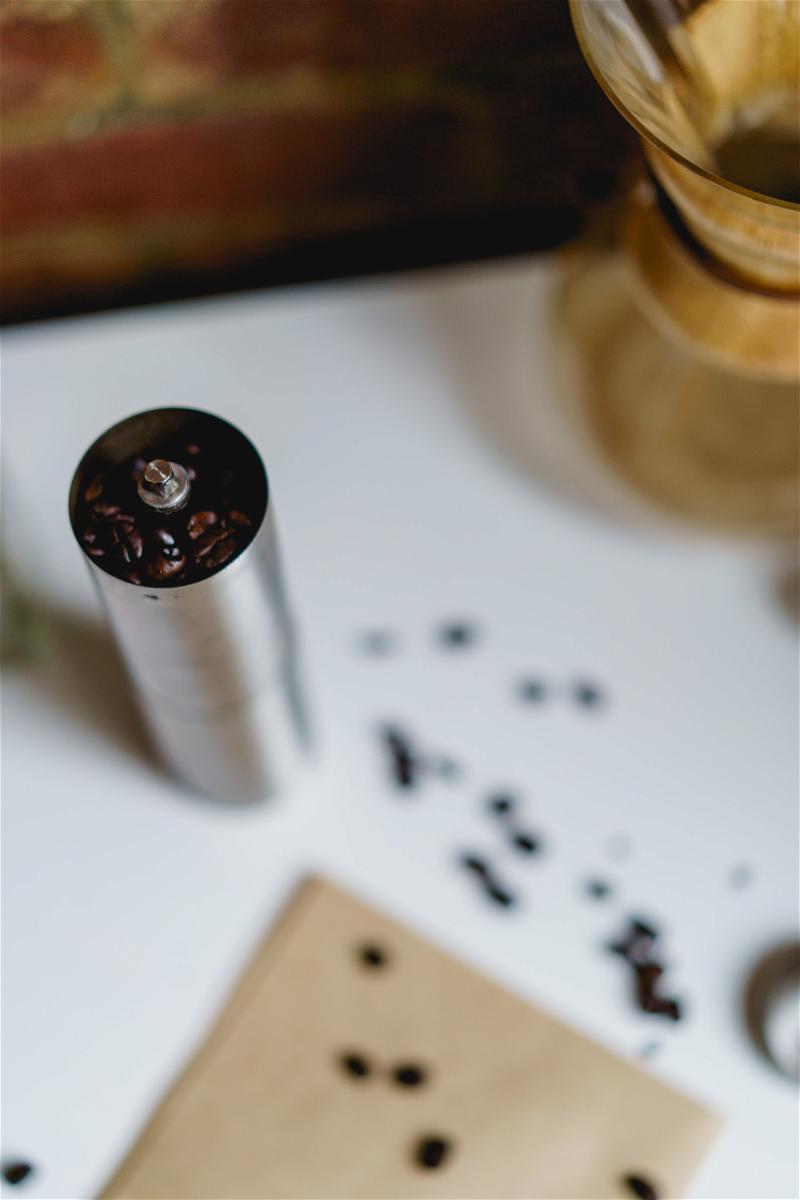A coffee grinder and coffee beans on a table.