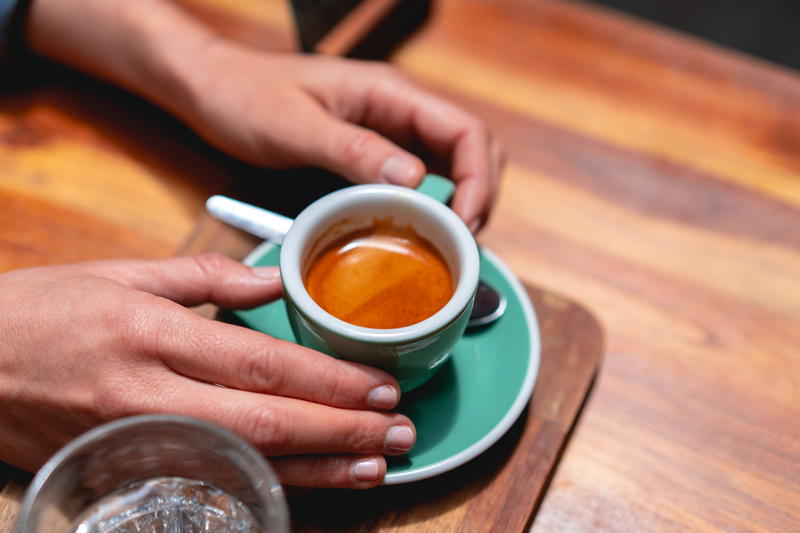 A person holding a cup of coffee on a wooden table.