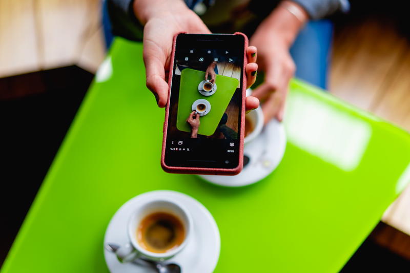 A person taking a picture of a cup of coffee.