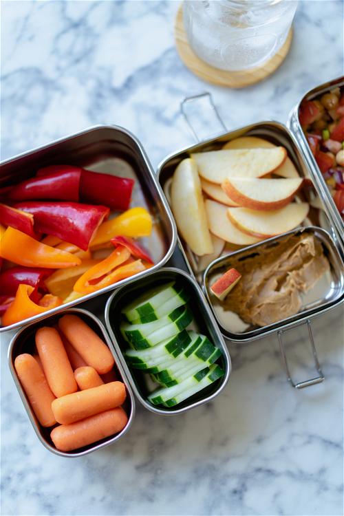 A tray with carrots, apples, and hummus.