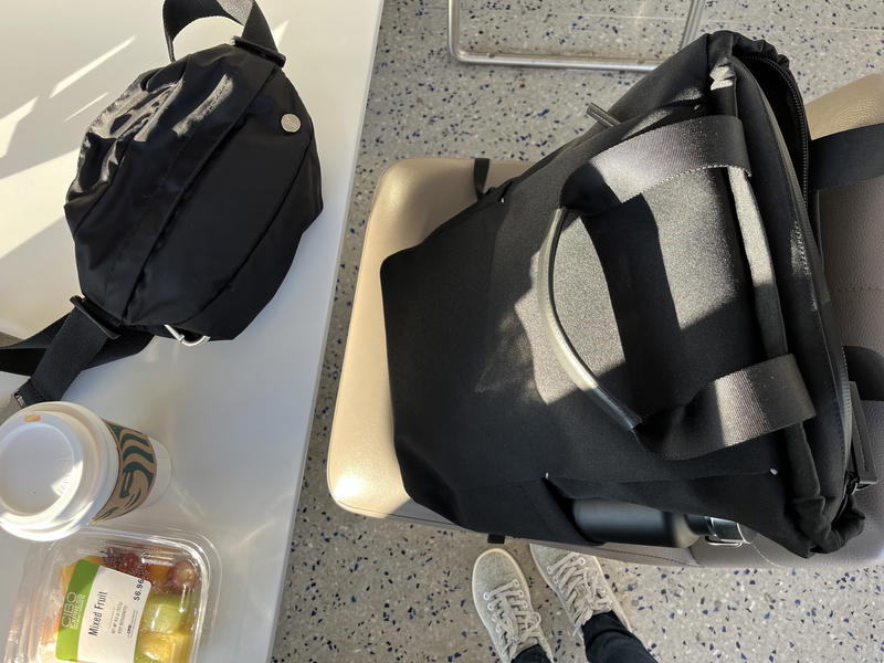 A black bag sitting on a table next to a person's feet.