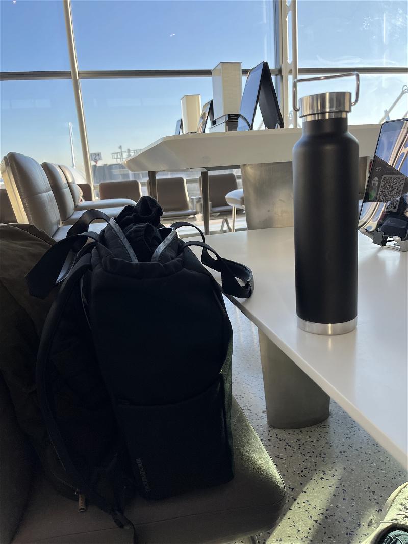 A backpack sits on a table next to a water bottle.