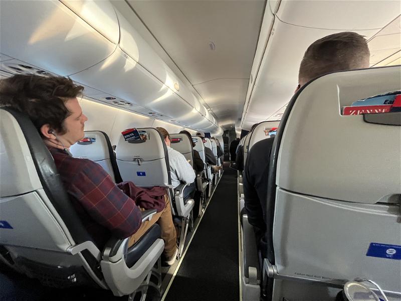 The inside of an airplane with people sitting in the seats.