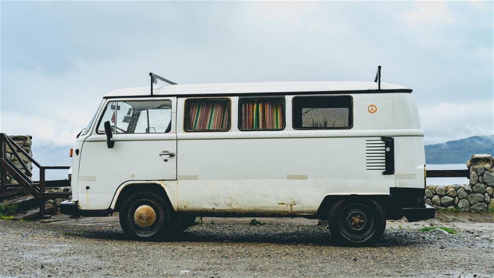A white vw bus parked on a gravel road.