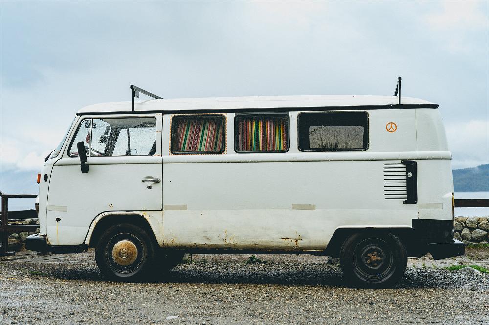 A white vw bus parked on a gravel road.