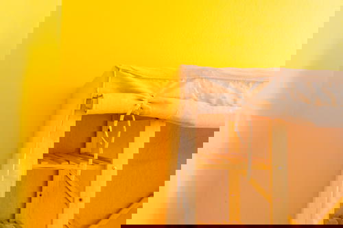 Yellow wall with light wooden bunk bed exterior and canvas cloth