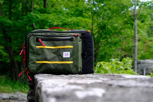 Topo Designs travel backpack on a stone ledge during a summer hiking scene