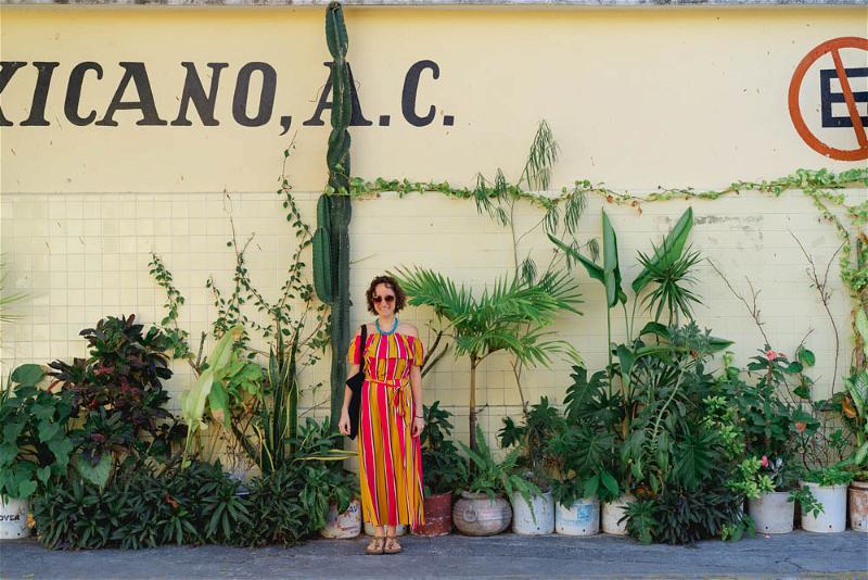 A woman in a striped dress standing in front of a mexican ac sign.