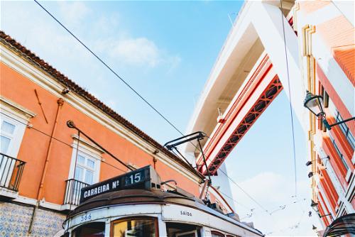 Orange Portuguese building next to a train skybridge and streetcar