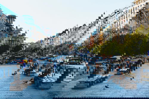 Plaza in downtown Prague lined with white stone buildings and benches for tourists