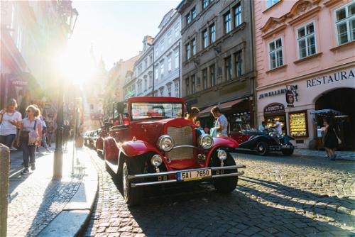 Vintage 1940s red car parked on a cobblestone street with a sun glare