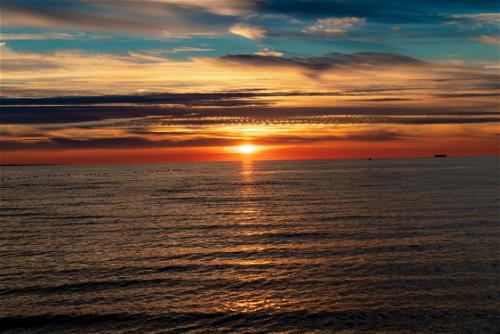 Sunset over an ocean with streaky clouds and bright orange colors