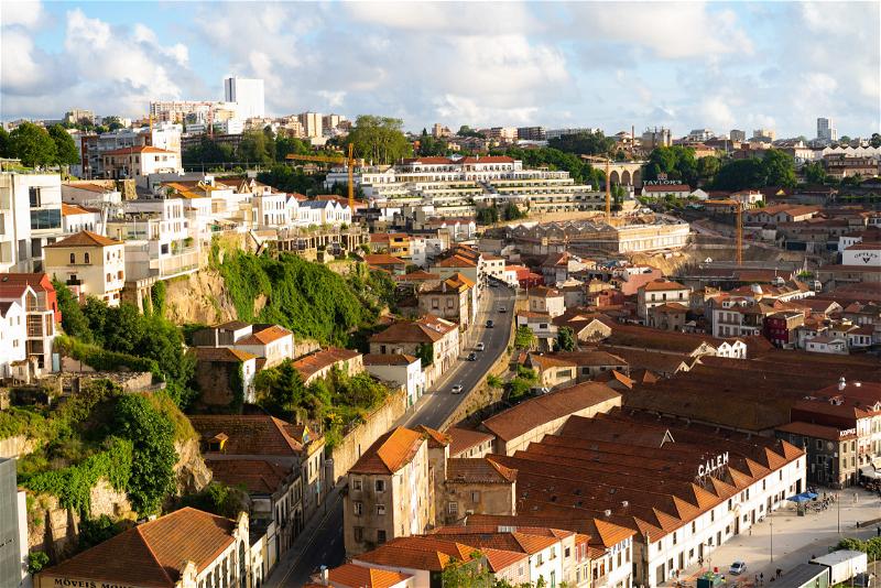 Golden hour in Porto Portugal, a view of red-roofed buildings and homes of Gaia among green cliffs