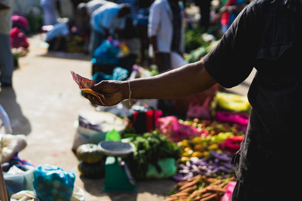 A man is handing out money at a market.