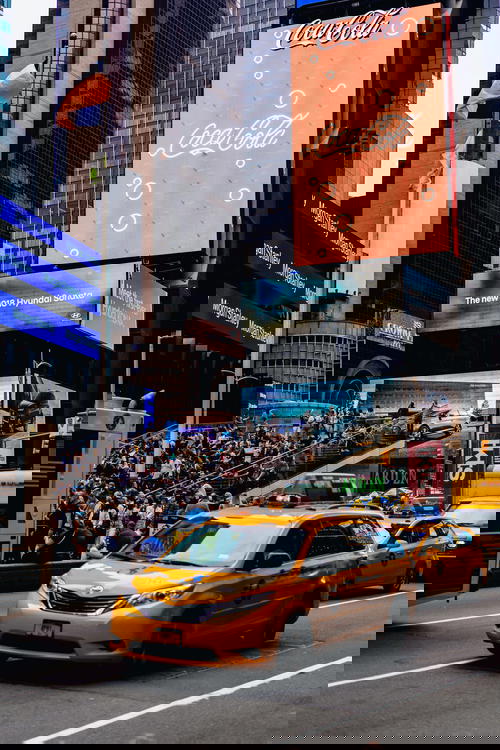 Times Square scene with a big Coca Cola billboard and yellow NYC minivan taxi