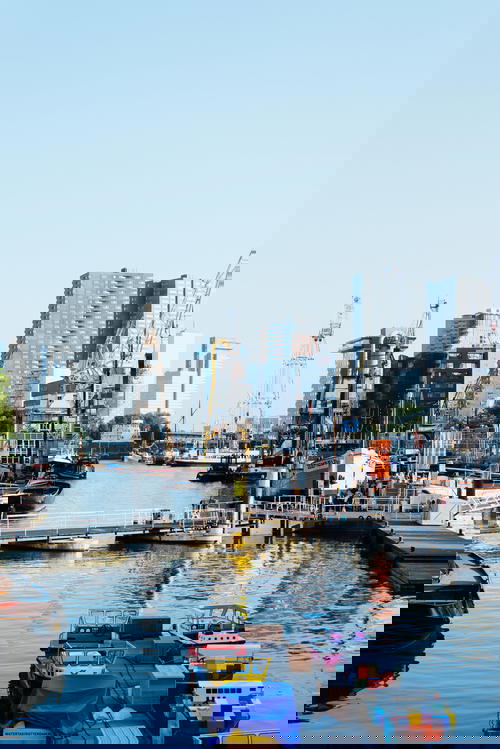 Skyscrapers, cranes, boardwalks and small river boats in the river of Rotterdam