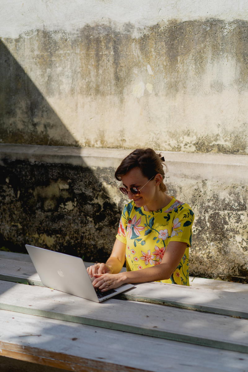 A woman sitting at a bench with a laptop.