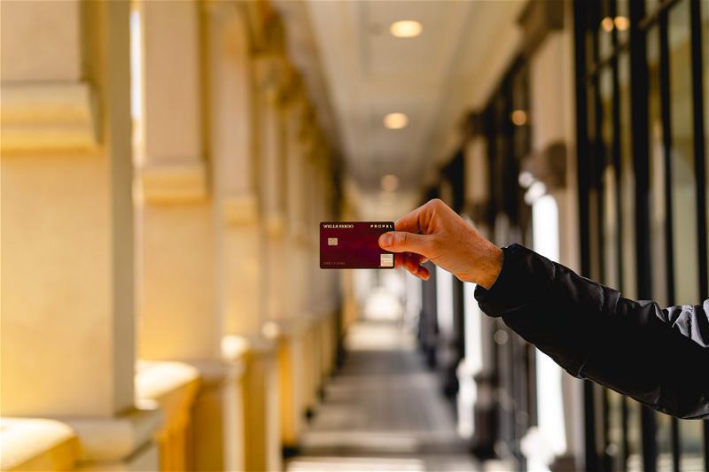 A man holding up a credit card in a hallway.