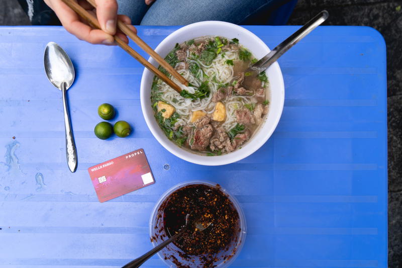 A person is eating a bowl of soup with chopsticks.