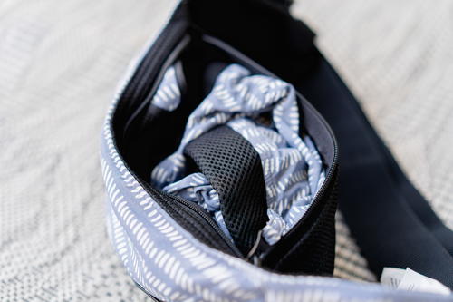 A blue and white fanny pack on a bed.