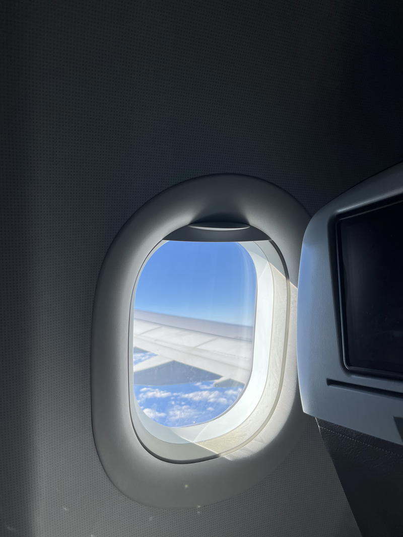 An airplane window with a view of the sky.