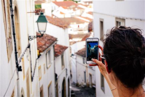 Women holding up a cell phone to take a photo of depth in a Portuguese village of white houses