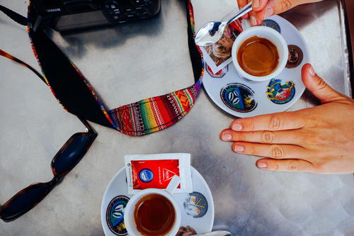 Camera strap and white cups of coffee at a cafe in Portugal