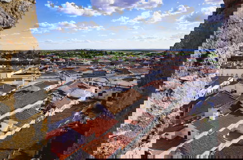 Blue sky dotted with white clouds above red tiled roofs in a Portuguese village