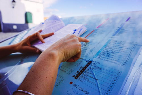 Using a book and a map to read directions for tourism in Portugal