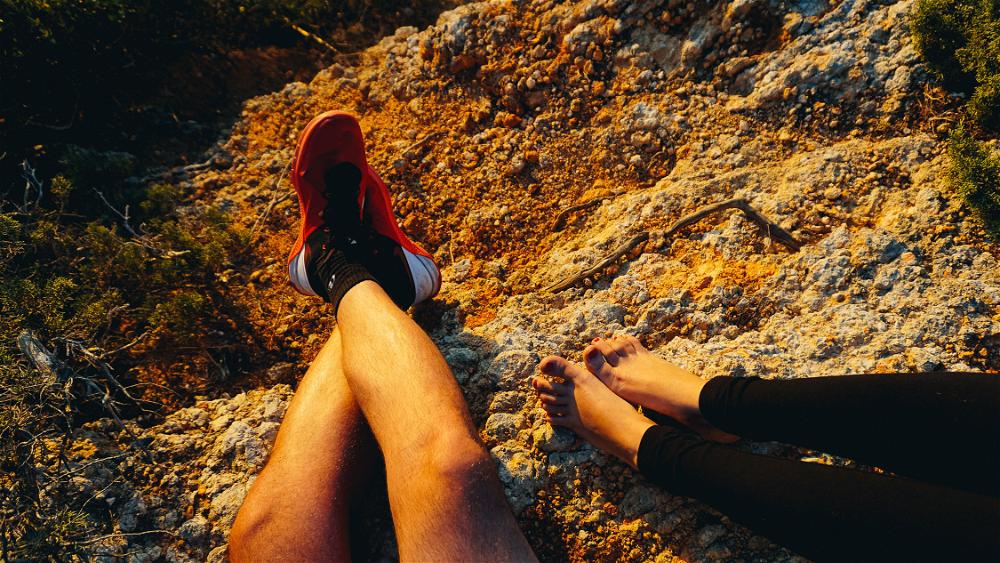 Feet of man and woman against rocks during sunset hour at cliffs